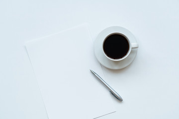 Cup of coffee, piece of paper and pen on the table. Top view