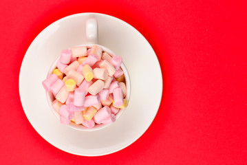 Cup with marshmallow on a red background. Copy space.