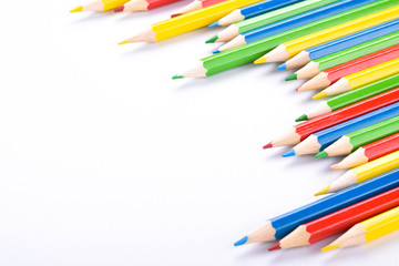 Many different colored pencils on a white background with a place for text and cory space .