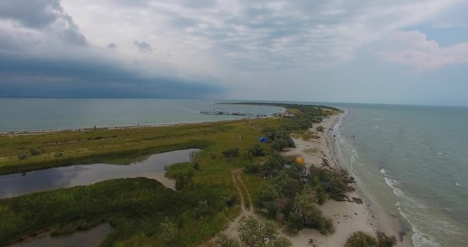 An amazing aerial view of a white beacon and a black border tower on Dzharylhach island with wonderful seacoast covered with green wetland and sand in summer. The skyscape is fine. Ukraine. 4k