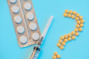 Pills and medical syringe on the blue background .