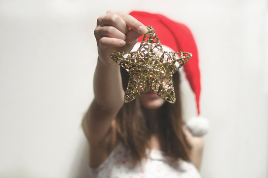 Girl wearing a santa Hat holding a Christmas star decoration