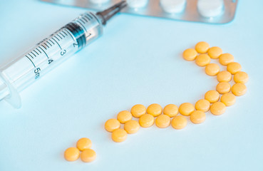 Pills and medical syringe on the blue background .