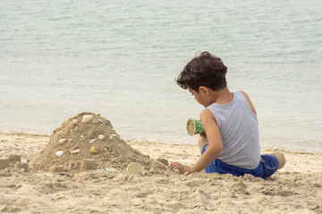 a Little boy playing on the beach with sands 