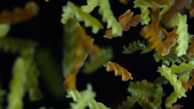 Macaroni in the Form of Drills. Italian pasta flies up and hang in front of the camera. Then fly away from the frame slowly into the darkness. Filmed at a speed of 480fps