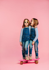 Twin girls together with skateboard - obrazy, fototapety, plakaty