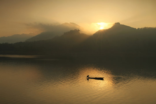 Silhouette of a fisherman fishing at Wadaslintang Lake, Central Java, Indonesia