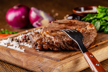 Italian cuisine. Juicy beef meat, veal steak on a wooden board with spinach, prunes and French mustard sauce. On the table is a glass of red pomegranate wine. Serving dishes in the restaurant