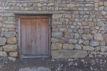 Fototapeta na wymiar Wall of a house built of various stones, clay and manure