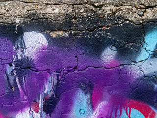 Purple, white and pink spray paint on a concrete wall.