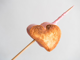 roasted heart form marshmallows on a skewer on white background