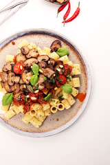 Penne pasta rigatoni in tomato sauce with mushrooms, tomatoes decorated with parsley and basil