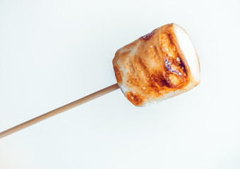 roasted marshmallows on a skewer in female hand on white background