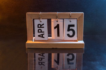 Wooden calendar with date 15th of April on dark