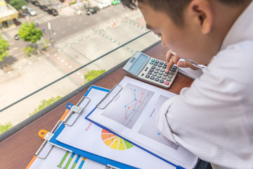 Young man using calculator to check many financial reports