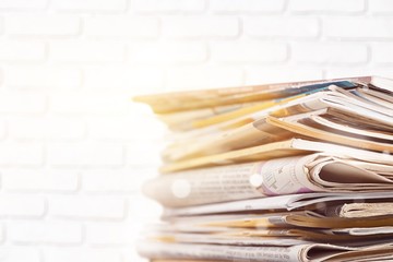 Pile of newspapers on blurred background, close up