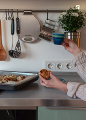 Woman is eating cinnamon roll and drinking coffee