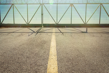 The fence with barbed wire. The road leading to the closed gate, a dead end.