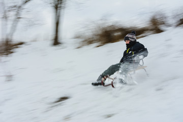 the boy descends from the hills in the sled, the movement is blurred