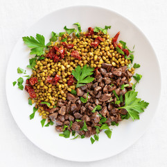 stewed in red wine chicken internal organs garnished  with green gram and decorated with dried tomato and parsley