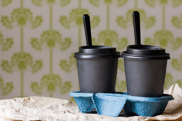 Two black paper cups filled with soup on a restaurant table
