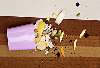Pink plastic trashcan on floor with scattered organic waste. Waste sorting and recycle at home for...