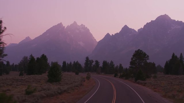 Driving along road in Grand Teton National Park at sunset