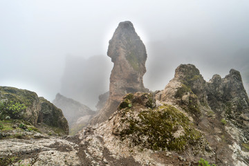 Nature mountain landscape of Canary Island with rock peak enveloping by dense fog 