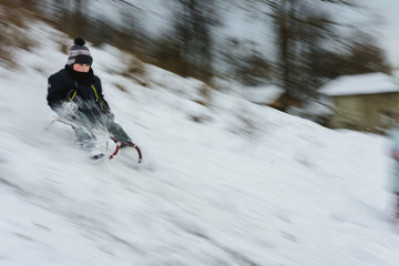 the boy descends from the hills in the sled, the movement is blurred