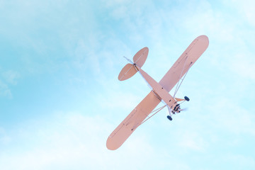 Retro plane with propeller flying and dives against the blue sky