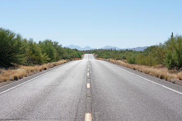 Paved road through the desert with mountains in the background