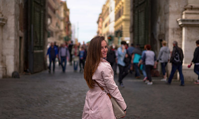 Fototapeta premium Piękny turysta spacerujący po Rzymie i uśmiechający się do kamery na tle tłumu. Włoska moda