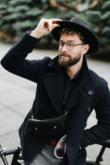 Handsome bearded young man in stylish outfit standing in the street with an fix gear bicycle