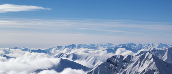 Panoramic view on snowy mountains in clouds