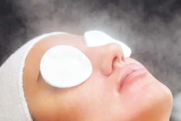 The procedure of steaming the skin of the face of a young woman before cleaning the skin in a...