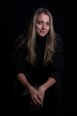 Naklejka premium Beautiful woman portrait in low light sitting on brown leather sofa