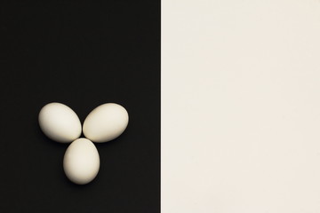 White chicken eggs on black part of contrasting black and white background. Minimalism style.