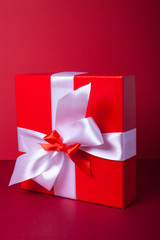 Gift box on red background. Valentine day, woman day gift. Red and white. ribbon, band.