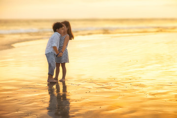 girl whispering to boy standing on the beach
