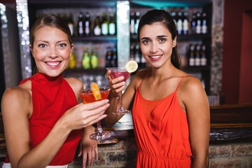 Female friends enjoying cocktail at counter in nightclub
