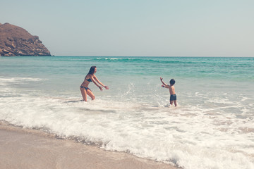 Fototapeta na wymiar mother and son splashing water in the sea