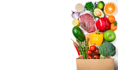 Healthy food background. Healthy food in paper bag meat beef, fruits, vegetables and pasta on white background. Shopping food supermarket concept. Long format with copy space