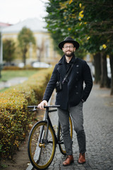 Enjoying the urban lifestyle. Young bearded man while sitting on his bicycle outdoors