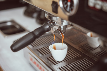 Professional espresso machine pouring fresh coffee into white ceramic cup