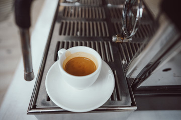 close-up view of glass cup with cappuccino and coffee machine