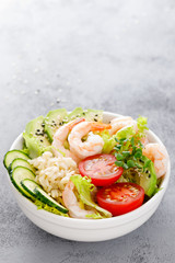 Hawaiian poke bowl with shrimps, rice and vegetables, healthy Buddha bowl with prawns, rice, avocado, cucumber, tomato and lettuce