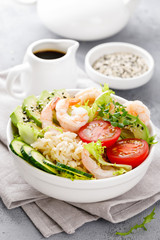 Hawaiian poke bowl with shrimps, rice and vegetables, healthy Buddha bowl with prawns, rice, avocado, cucumber, tomato and lettuce