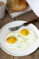 Breakfast of fried eggs, bread toasts and coffee on a wooden table. Rustic style.