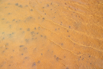 Background with red sands of volcanic origin, stones and ocean water.