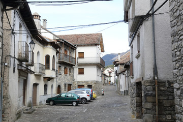 A rural landscape of a Pyrenees mountain hamlet with stone houses with wooden balconies and dark roofs during winter in Ansó, Aragon region, Spain